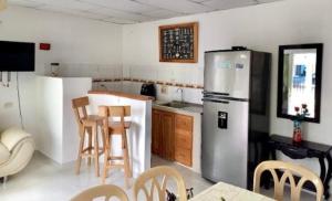 a kitchen with a refrigerator and a table and chairs at Cabañas Ypaos in Coveñas