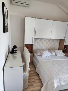 ein Schlafzimmer mit einem weißen Bett und einem weißen Schreibtisch in der Unterkunft Apartmani Seka in Vodice