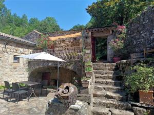 a stone building with a table and an umbrella at Aqua Terra Silva in Gravières