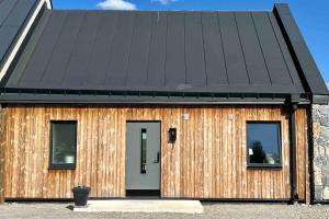 une maison en bois avec un toit noir et deux fenêtres dans l'établissement Fint hus nära Järvsöbacken, à Järvsö