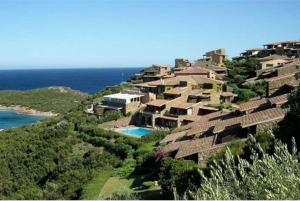a house on a hill next to the ocean at By the sea with amazing view in Capo Coda Cavallo