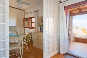 a kitchen and dining room with a table and a window at By the sea with amazing view in Capo Coda Cavallo +10 photos