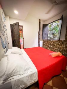 um quarto com uma cama grande e um cobertor vermelho em Casa del Pozo Azul em Minca