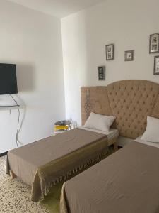 a hotel room with two beds and a tv at Studio CoCoti in Tataouine