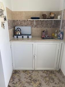una cocina con armarios blancos y fregadero en Studio CoCoti, en Tataouine