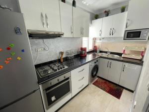 a kitchen with white cabinets and a stove top oven at Location appartement Alhoceima in Al Hoceïma