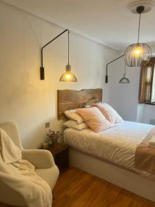 1 dormitorio con 1 cama, 1 silla y 2 luces en APARTAMENTO TURÍSTICO SAN NICOLAS, en Avilés