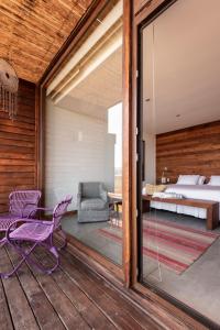 1 dormitorio con balcón con cama y puerta de cristal en Hotel Alaia, en Pichilemu