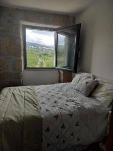 een slaapkamer met een bed en een groot raam bij Arpuro in Gouveia