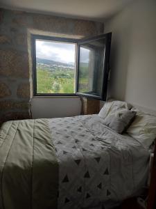 a bedroom with a bed and a large window at Arpuro in Gouveia