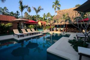 a pool at a resort with chairs and umbrellas at Bungalow LUXURY cerca a la Playa Zihuatanejo Mexico in Ixtapa