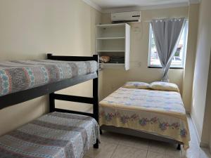 um pequeno quarto com 2 beliches e uma janela em Residencial Recanto do Sossego em Bombinhas