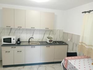 a kitchen with white cabinets and a sink and a microwave at Casa Eva in Bucureşci