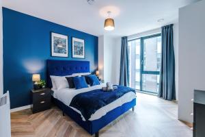 a blue bedroom with a bed and a blue wall at Luxury City Central Apartment. Roof Terrace, Gym, Cinema room + Games Area in Sheffield