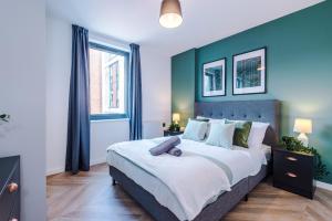 a bedroom with a large bed with a blue wall at Luxury City Central Apartment. Roof Terrace, Gym, Cinema room + Games Area in Sheffield