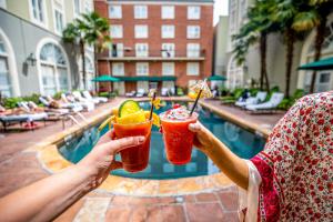 two people holding drinks in their hands near a pool at Bourbon Orleans Hotel in New Orleans