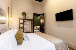 1 dormitorio con 1 cama blanca y TV de pantalla plana en Union St Lofts, en Nashville