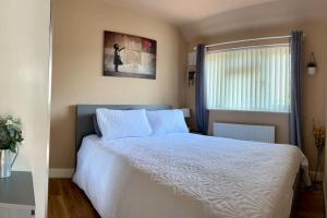 - une chambre avec un lit blanc et une fenêtre dans l'établissement Heathrow's Nest, à Hayes