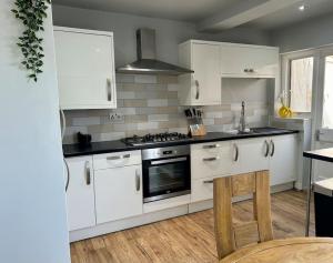 una cucina con armadi bianchi e piano cottura di Heathrow's Nest a Hayes
