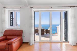a living room with a couch and a view of the ocean at Apartments Grloman in Sveti Stefan