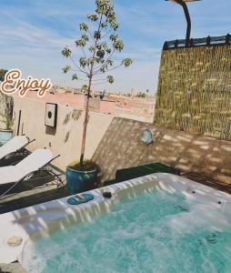 uma banheira de hidromassagem num pátio com uma árvore em DAR Riad Jomana em Marrakech