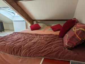 a large bed with red pillows in a room at Penty breton cosy in Plougonvelin