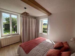 Un dormitorio con una cama y dos ventanas. en Le Petit Portais, en Port-en-Bessin-Huppain