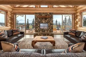 a living room with leather furniture and a stone fireplace at Majestic Valley Wilderness Lodge in Sutton
