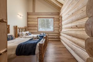 a log cabin bedroom with two beds and a window at Majestic Valley Wilderness Lodge in Sutton