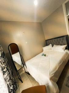 Kiambu的住宿－Tsavo coral bells one bedroom apartment，一间卧室配有一张带白色床单和椅子的床