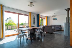 Un comedor con una mesa y sillas y un sofá. en Cocon vert proche mer, en Plouhinec