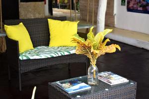 a wicker couch with yellow pillows and a vase with a plant on at Hotel Beach Energy 5th Av in Playa del Carmen