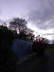 un petit bâtiment bleu avec un arbre derrière dans l'établissement Camping du Puy Rond, à Bressuire
