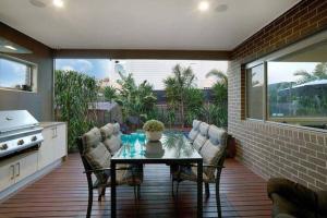 Un patio con mesa y sillas y una cocina. en Dromana Grove SPA & POOL sleeps 15, en Dromana