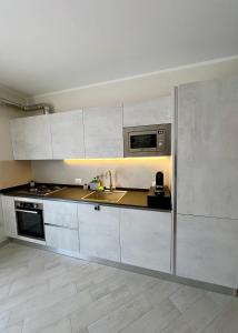 a kitchen with white cabinets and a sink and a microwave at NOVIMO Comfort Apartment with elevator and secure privat parking space in Terrasini +24 photos