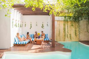 a group of people sitting in chairs next to a swimming pool at Lula Seaside Boutique Hotel in Tulum