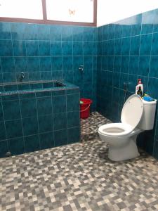 bagno con servizi igienici e pavimento piastrellato blu di Guesthouse Jagabaya a Kuningan