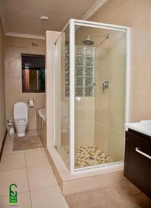 uma casa de banho com uma cabina de duche em vidro e um WC. em Su's Crest em Blantyre