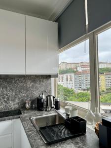 een keuken met witte kasten, een wastafel en een raam bij WORK&STAY - Apartamento no centro de Coimbra in Coimbra