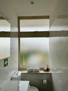 een badkamer met een toilet en een groot raam bij WORK&STAY - Apartamento no centro de Coimbra in Coimbra