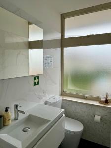 een badkamer met een wastafel, een toilet en een raam bij WORK&STAY - Apartamento no centro de Coimbra in Coimbra