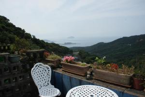 two white chairs sitting on a balcony with flowers at Jiufen Walk Inn 3x3 in Jiufen