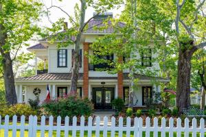 a white picket fence in front of a house at Historic Huntington Home with Pond and Flower Gardens! in Zavalla