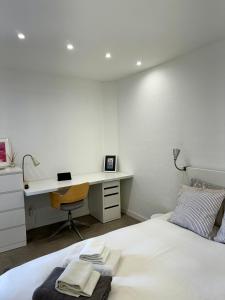 een witte slaapkamer met een bureau en een bed bij WORK&STAY - Apartamento no centro de Coimbra in Coimbra