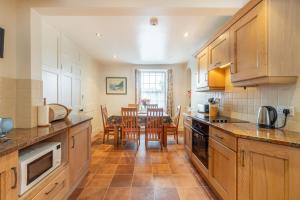 eine Küche mit Holzschränken und einem Tisch mit Stühlen in der Unterkunft Hillside Cottage in Ambleside
