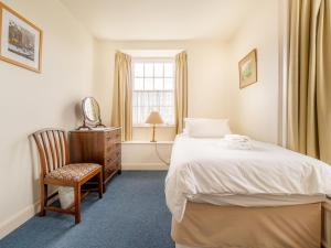 ein Schlafzimmer mit einem Bett und einem Stuhl und einem Fenster in der Unterkunft Hillside Cottage in Ambleside