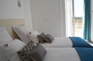 a bedroom with a bed with pillows and a window at Entre Vinhas & Mar in Óbidos