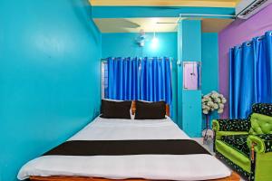 OYO Mohona Residency & Restaurant في Nimtita: غرفة نوم بسرير وجدار ازرق