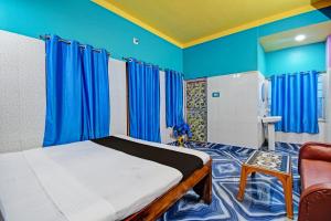 OYO Mohona Residency & Restaurant في Nimtita: غرفة نوم بجدران زرقاء وسرير وكرسي
