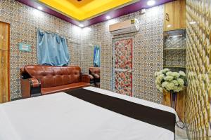 OYO Mohona Residency & Restaurant في Nimtita: غرفة نوم بسرير وكرسي جلدي